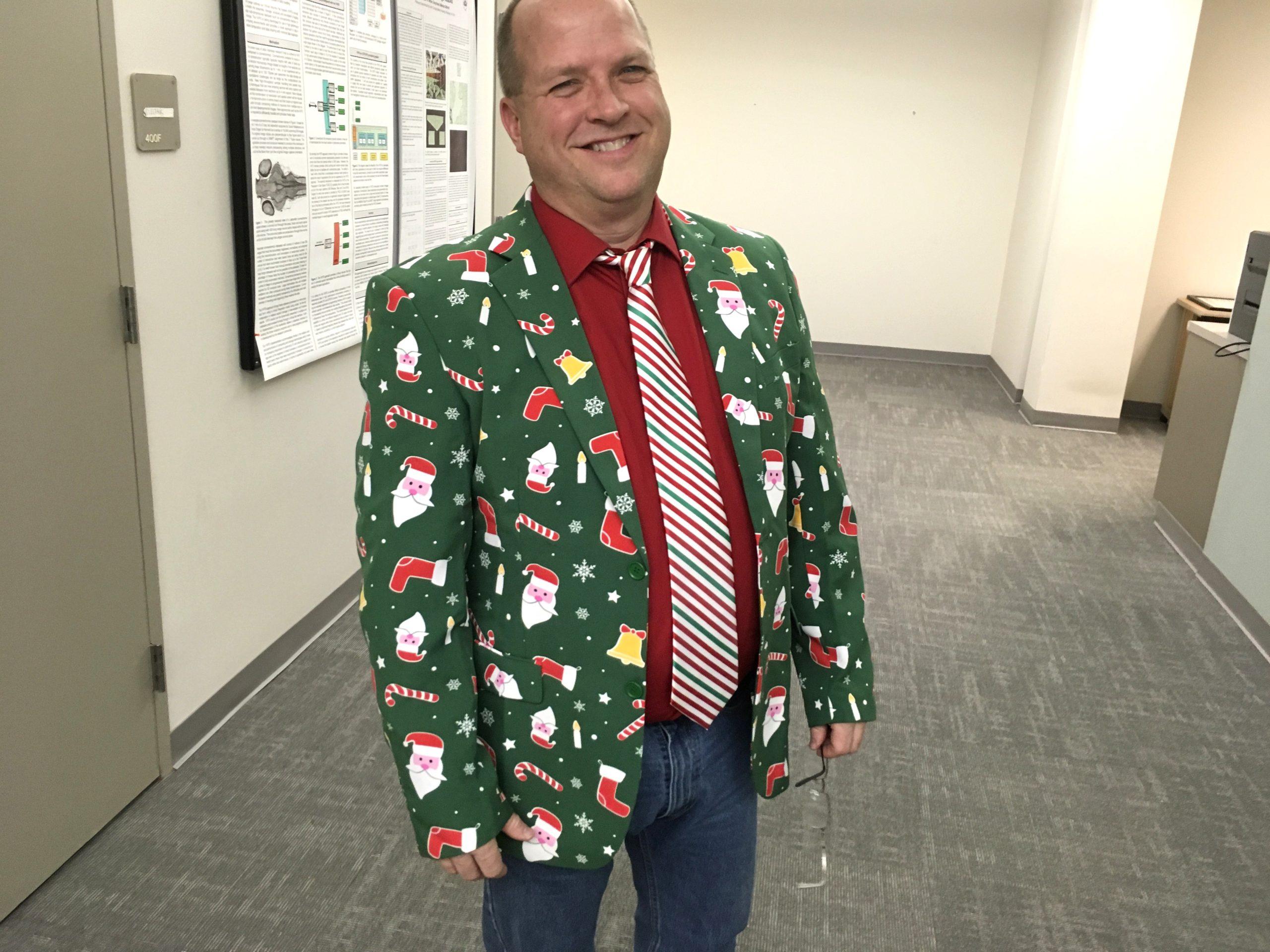 Ken smiles while wearing a brightly colored suit with Santa Claus and candy cane motifs.