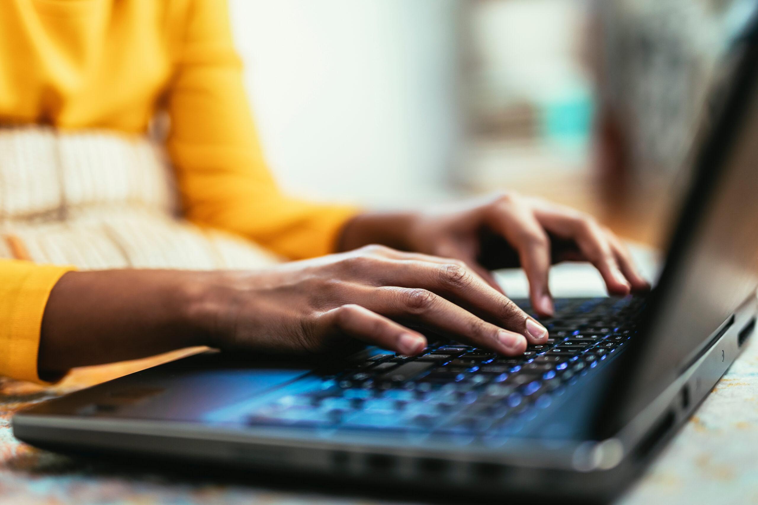 Hands typing at a laptop